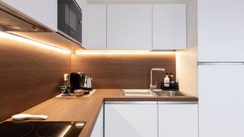 A modern kitchen with a wooden countertop, a built-in stove, a sink, and white cabinets.