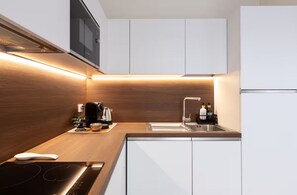 A modern kitchen with a wooden countertop, a built-in stove, a sink, and white cabinets.