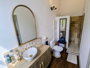 A bathroom with a large mirror, a white sink with a gold faucet, a toilet, and a shower area. - Domaine de la Dordrona (Bourdeilles)