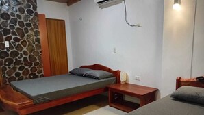Ein Schlafzimmer mit einem Einzelbett, einem Nachttisch aus Holz, einem kleinen Tisch und einer Steinwand.