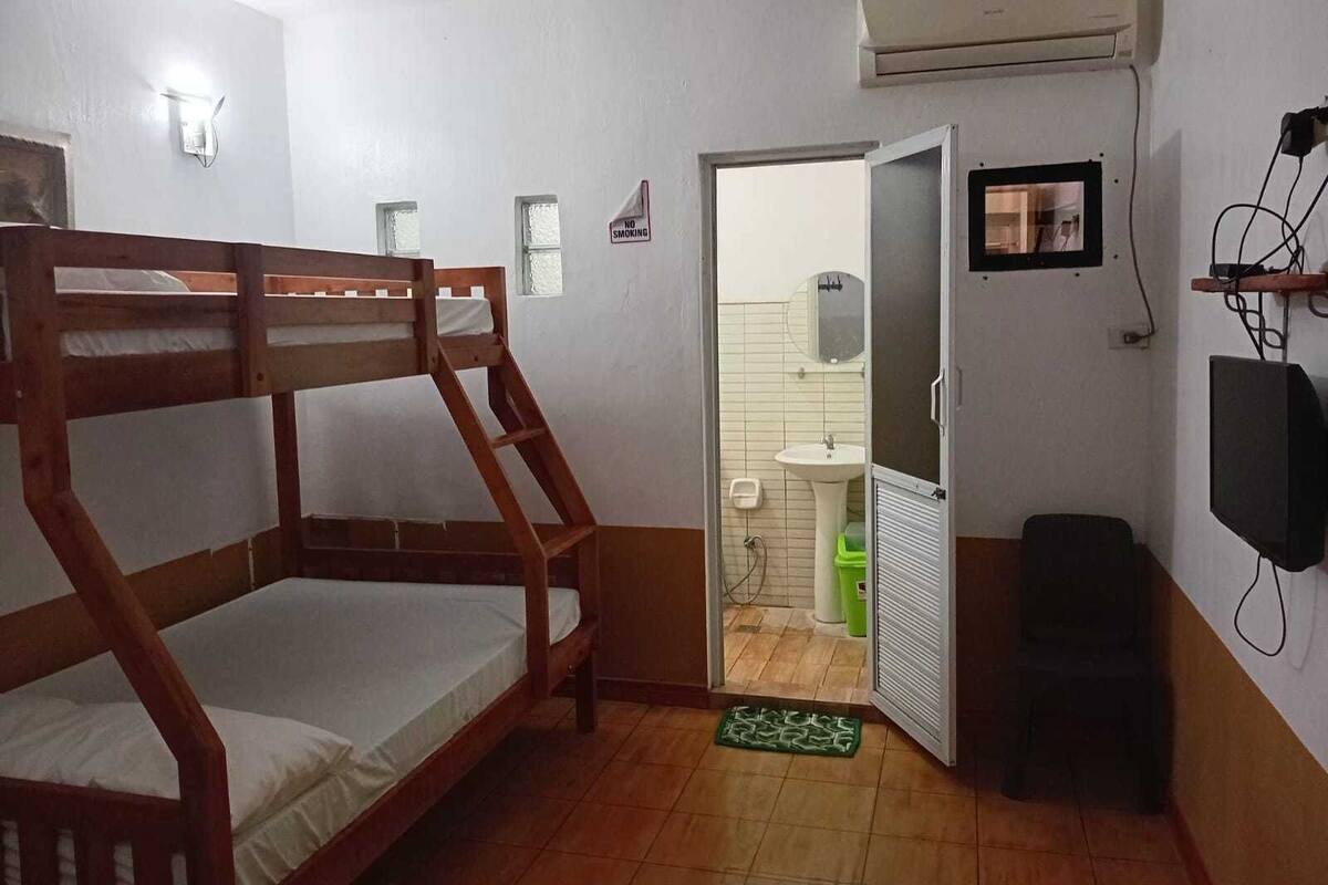 Une chambre avec un lit superposé, un petit lavabo et une porte donnant sur une salle de bain.
