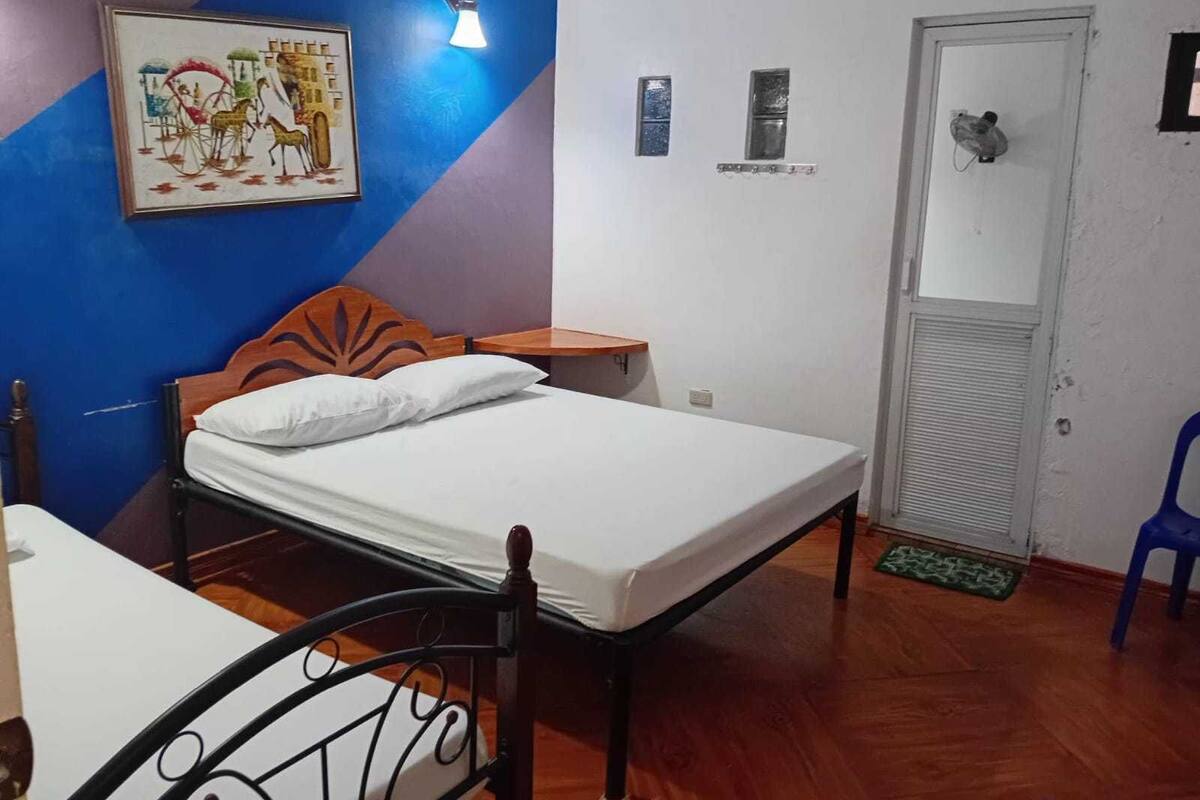 Une chambre à coucher comprenant un lit, une chaise, un bureau, une lampe fixée au mur et une porte.