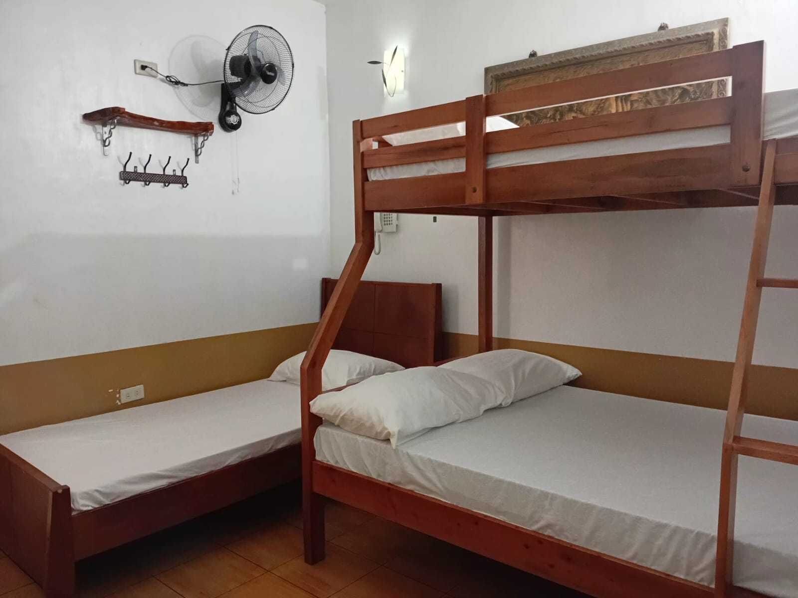 A bunk bed room with a wooden headboard, a wall-mounted fan, and a telephone.