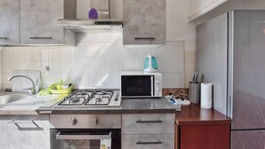 Et køkken med gaskomfur, mikroovn og stålrefrigerator.