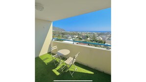 A balcony with a view of the sea and cityscape, a small table, and two chairs. - La Verrière with its panoramic view! (Saint-Denis)