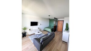 A modern living room with a grey sofa, a white coffee table, and a TV mounted on the wall. - La Verrière with its panoramic view! (Saint-Denis)
