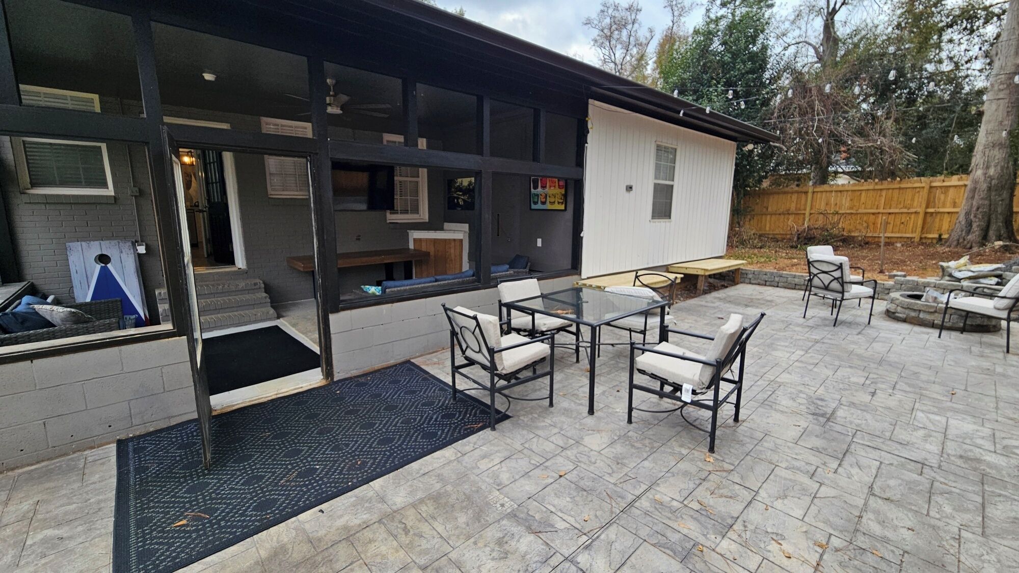 A patio with outdoor furniture, a glass door entrance, and a wooden fence in the background.