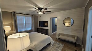 A bedroom with a bed, a ceiling fan, a TV, a chair, and a mirror. - Fabulous 3-bedrm In town/Masters 1 mle Bungalow new VRBO & SUPERhost on Air BB (Augusta)