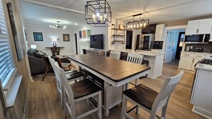 A modern kitchen with white cabinets, a central island, and a dining area with a wooden table and white chairs. - Fabulous 3-bedrm In town/Masters 1 mle Bungalow new VRBO & SUPERhost on Air BB (Augusta)