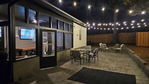 An outdoor patio area with a table and chairs, a black mat, and string lights. - Fabulous 3-bedrm In town/Masters 1 mle Bungalow new VRBO & SUPERhost on Air BB (Augusta)