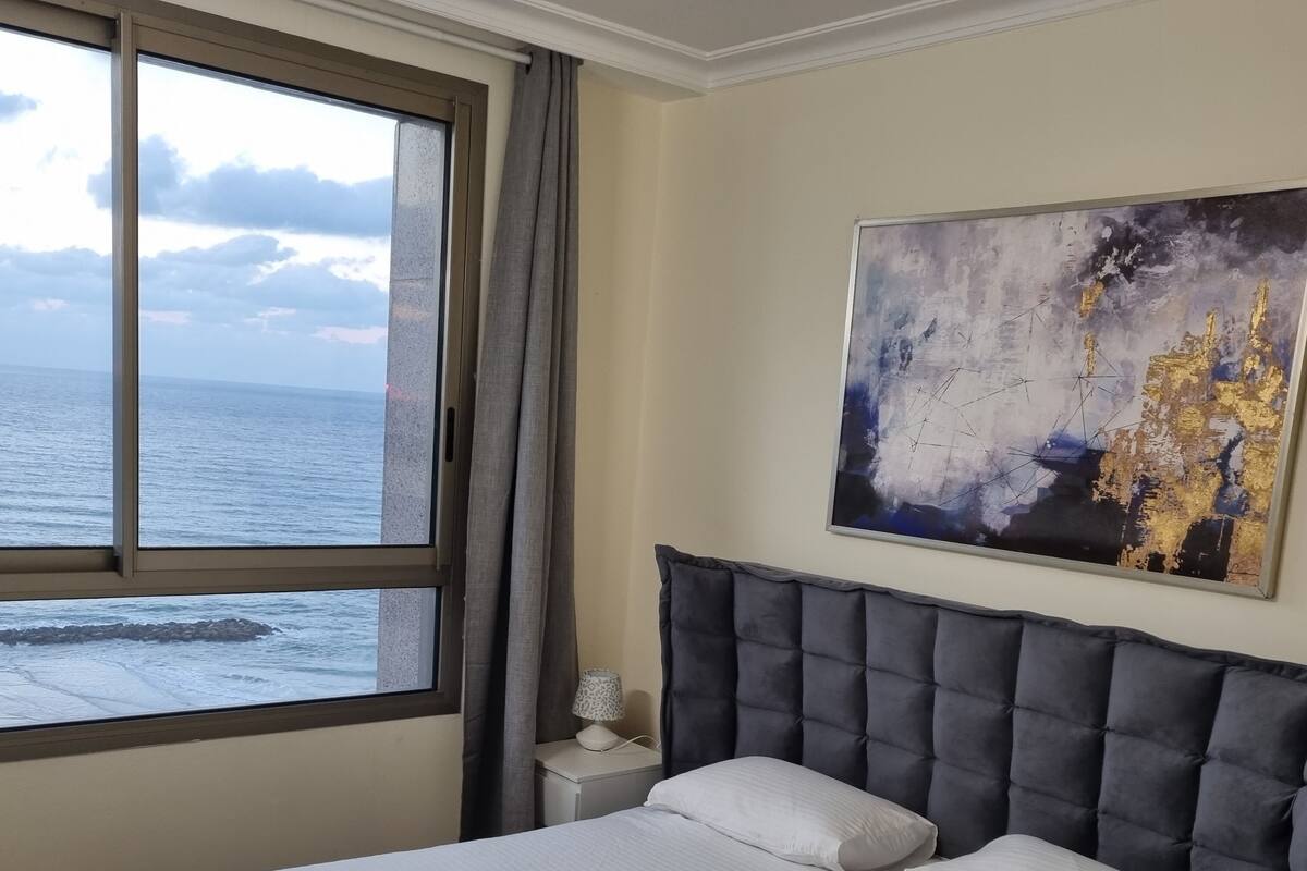 Une chambre à coucher avec un grand lit, une table de chevet, une lampe et un tableau.