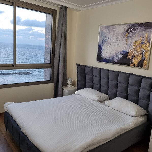 Un dormitorio con una cama grande, una mesita de noche, una lámpara y un cuadro.