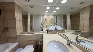 A modern bathroom with a large mirror, dual sinks, a toilet, and a shower.