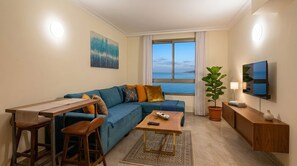 A modern living room with a sofa, a coffee table, a TV, and a large window with a view of the sea. - Sea Tower Almog (Haifa)