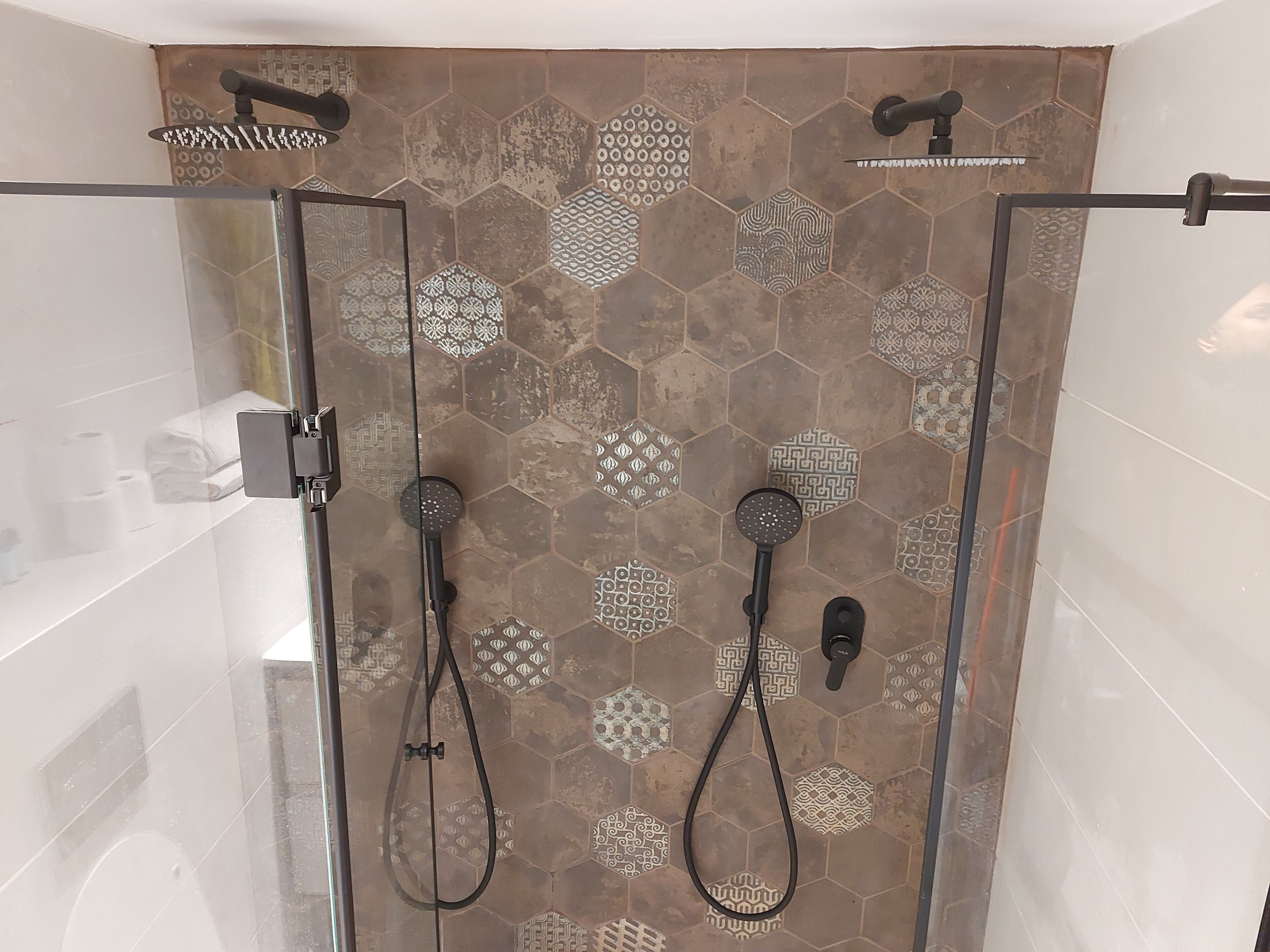 Ducha con puerta de cristal y un diseño de azulejos hexagonales.
