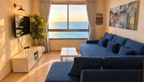 A living room with a sofa, a coffee table, a TV, and a plant. - Sea Tower Almog (Haifa)
