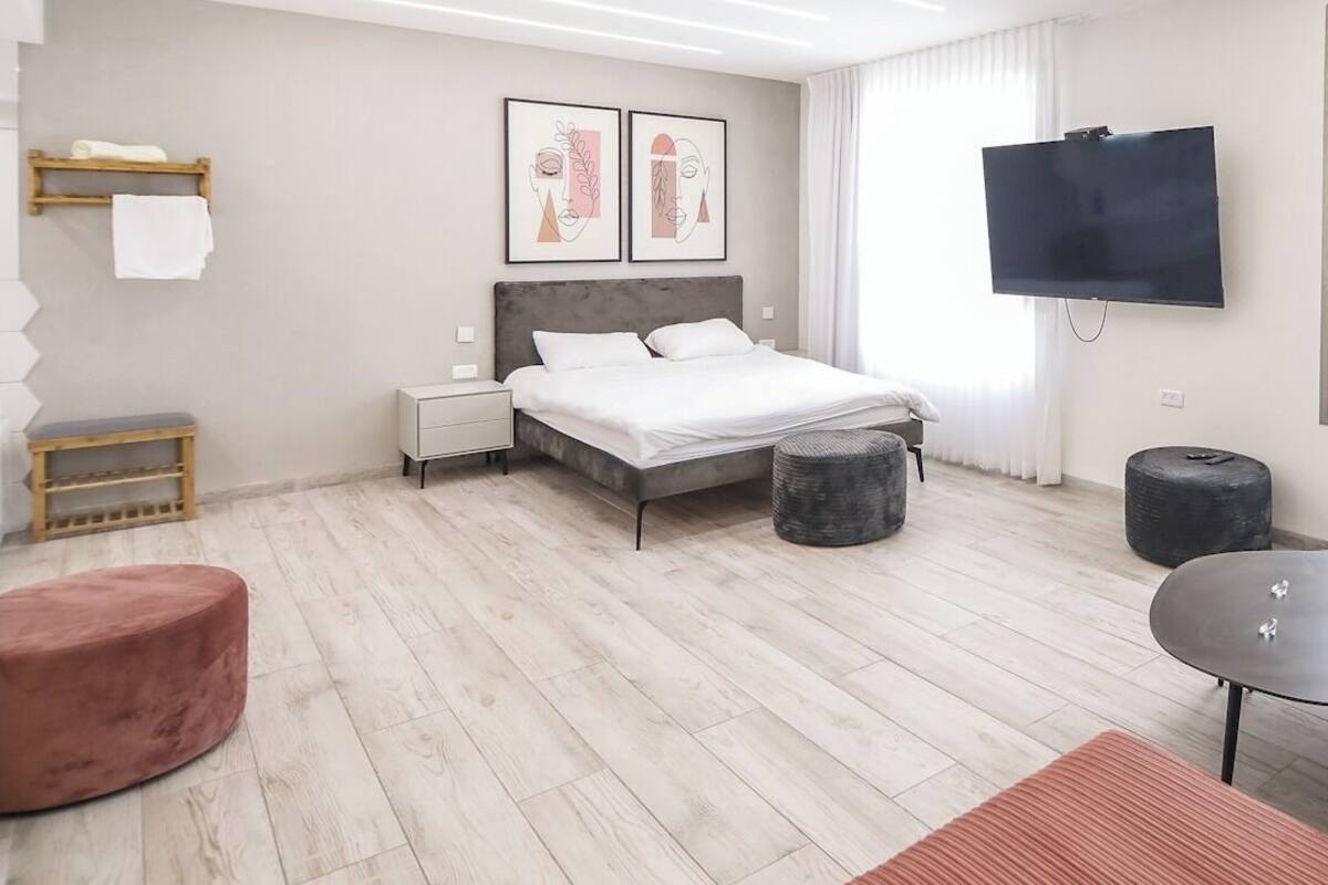 Une chambre moderne avec un lit, des tables de chevet, un téléviseur et un plancher en bois.