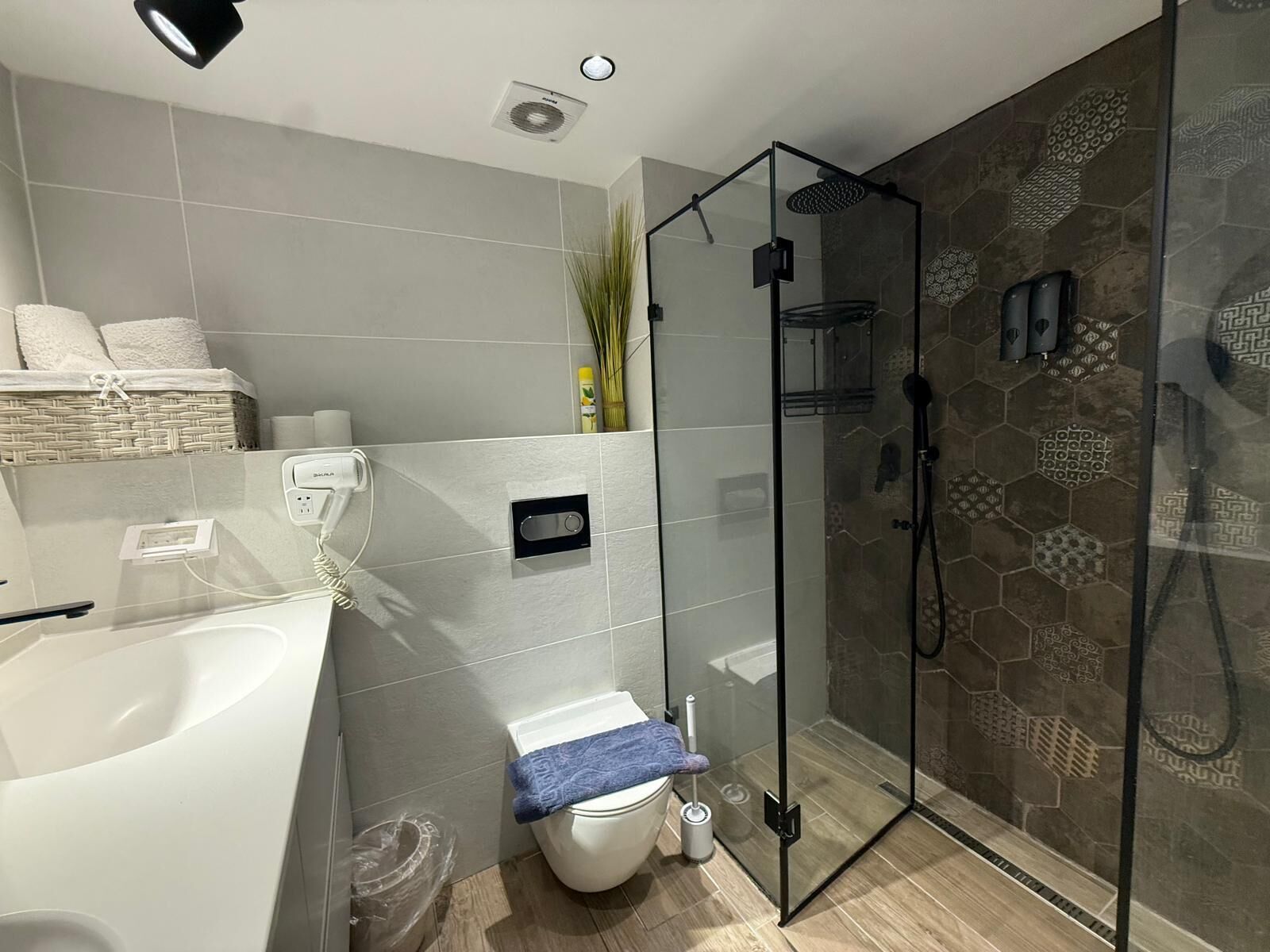 A modern bathroom with a glass-enclosed shower, a white bathtub, and a toilet.