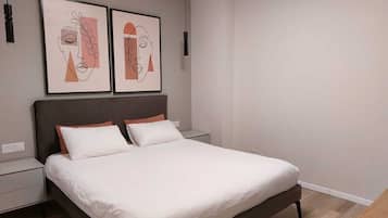 A modern bedroom with a large bed, two bedside tables, and two wall-mounted artworks.