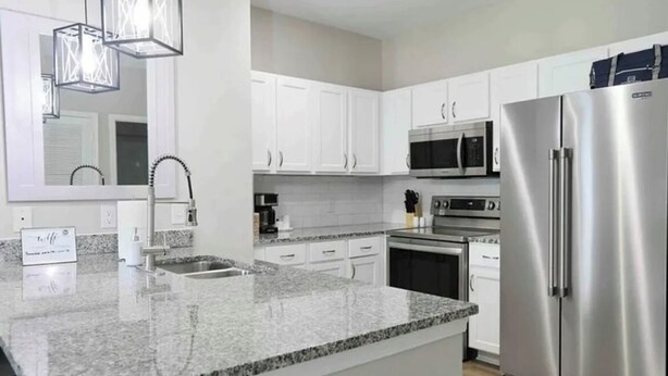 A modern kitchen with white cabinets, stainless steel appliances, granite countertops, and pendant lighting. - 2 miles from campus and the square.Cozy 2 BR/2BA in popular Rowendale community (Oxford)