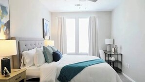 A bedroom with a bed, nightstand, lamp, and a window with curtains. - 2 miles from campus and the square.Cozy 2 BR/2BA in popular Rowendale community (Oxford)