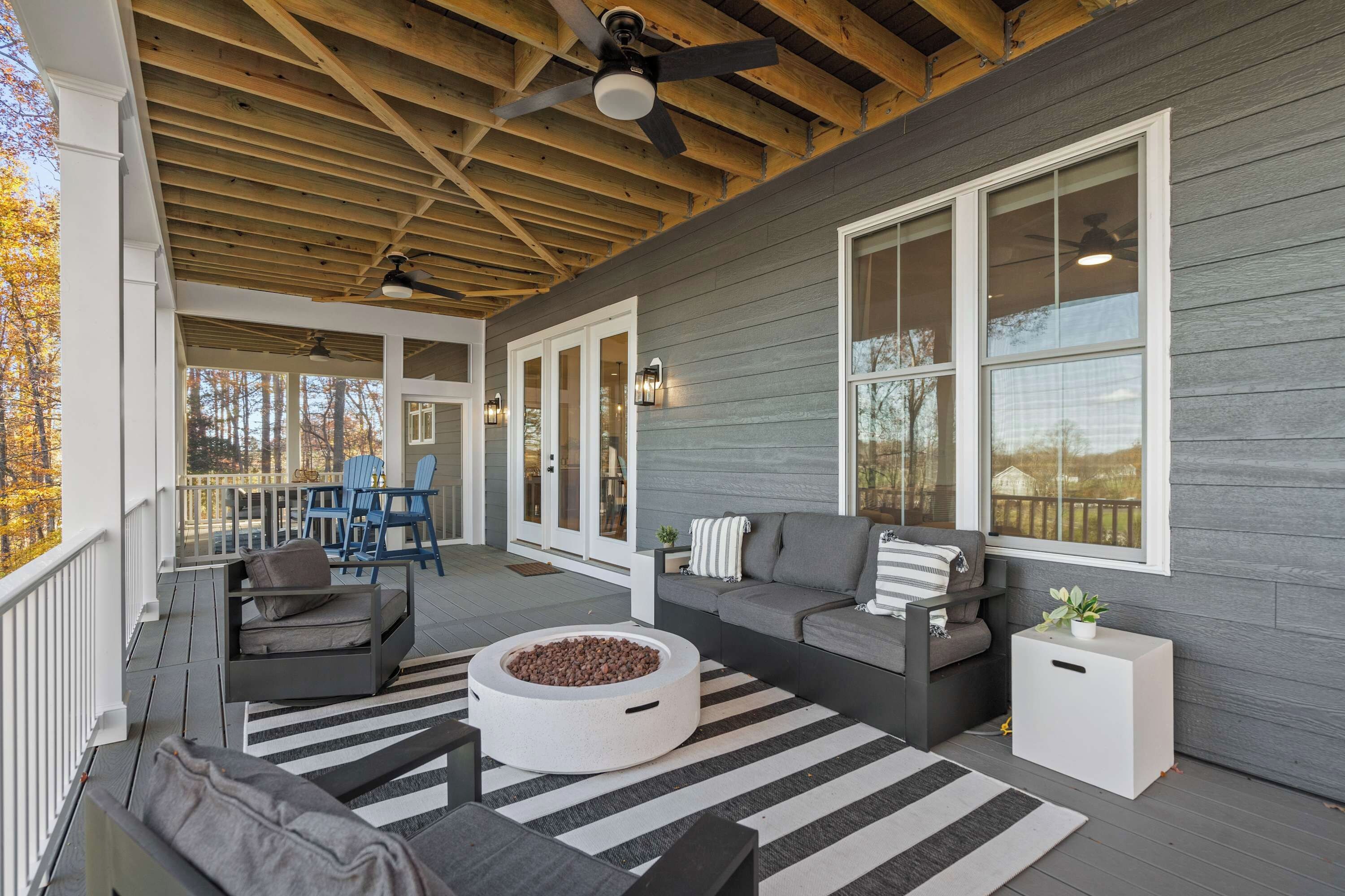 Outdoor Living - The lower deck lounge with a fire pit, striped rug, and French doors leading back inside.