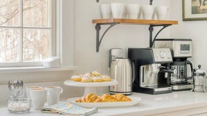 Eine Küchenarbeitsplatte mit Kaffeemaschine, Wasserkocher und einer Auswahl an Gebäck.