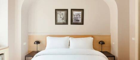 A bedroom with a large bed, two bedside tables, and two framed pictures on the wall.