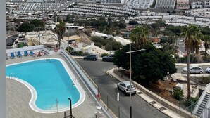 Una zona residencial con piscina, carretera y un paisaje montañoso al fondo.
