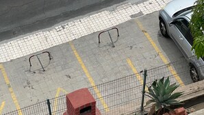 Un horno de ladrillo con una chimenea, dos sillas de plástico y una silla blanca de plástico cerca de una valla.