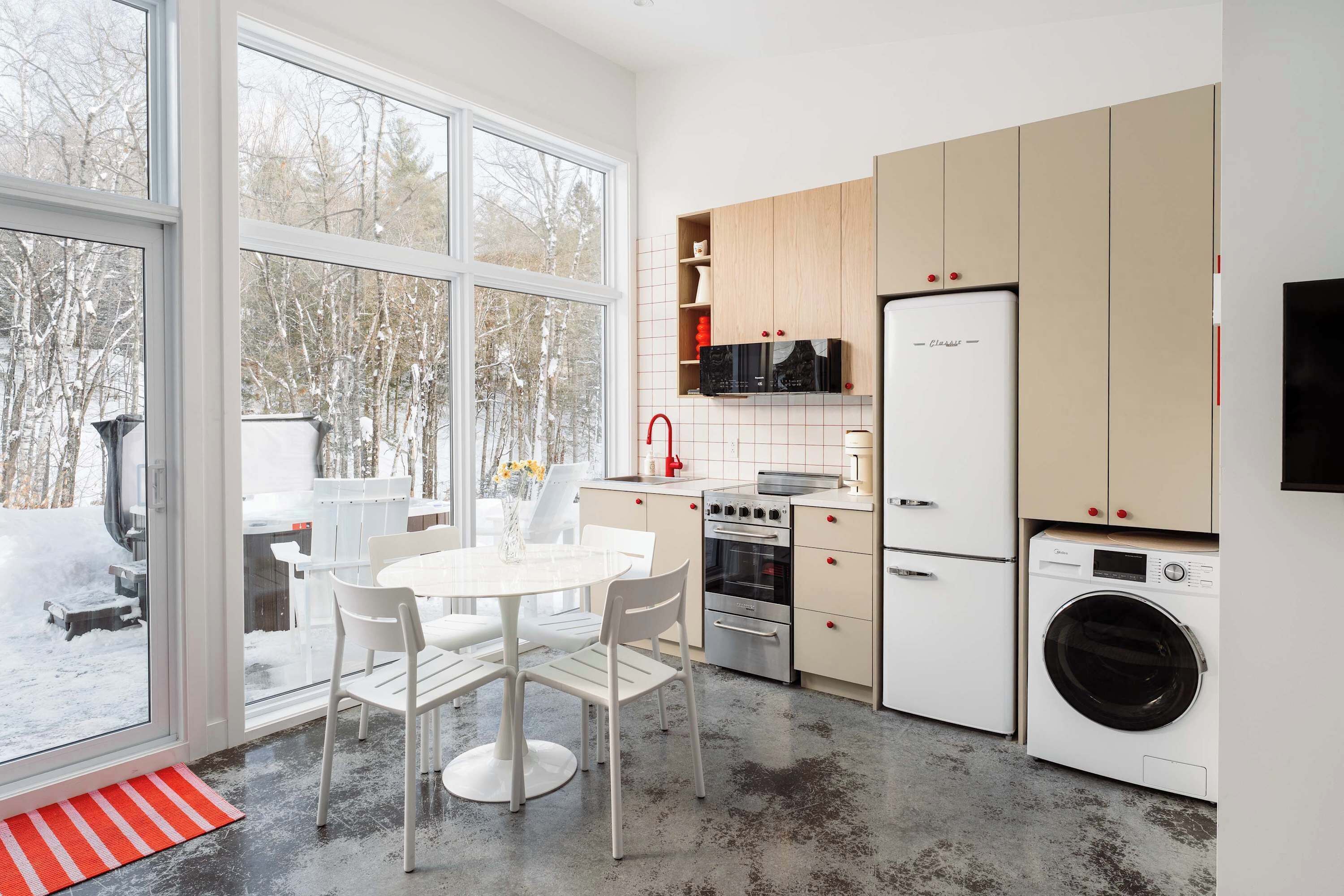 Una cocina moderna con armarios blancos, un horno de acero inoxidable, un microondas, un refrigerador y una lavadora.