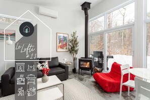 Una sala moderna con chimenea, un sofá, un sillón de peluche rojo y un comedor.