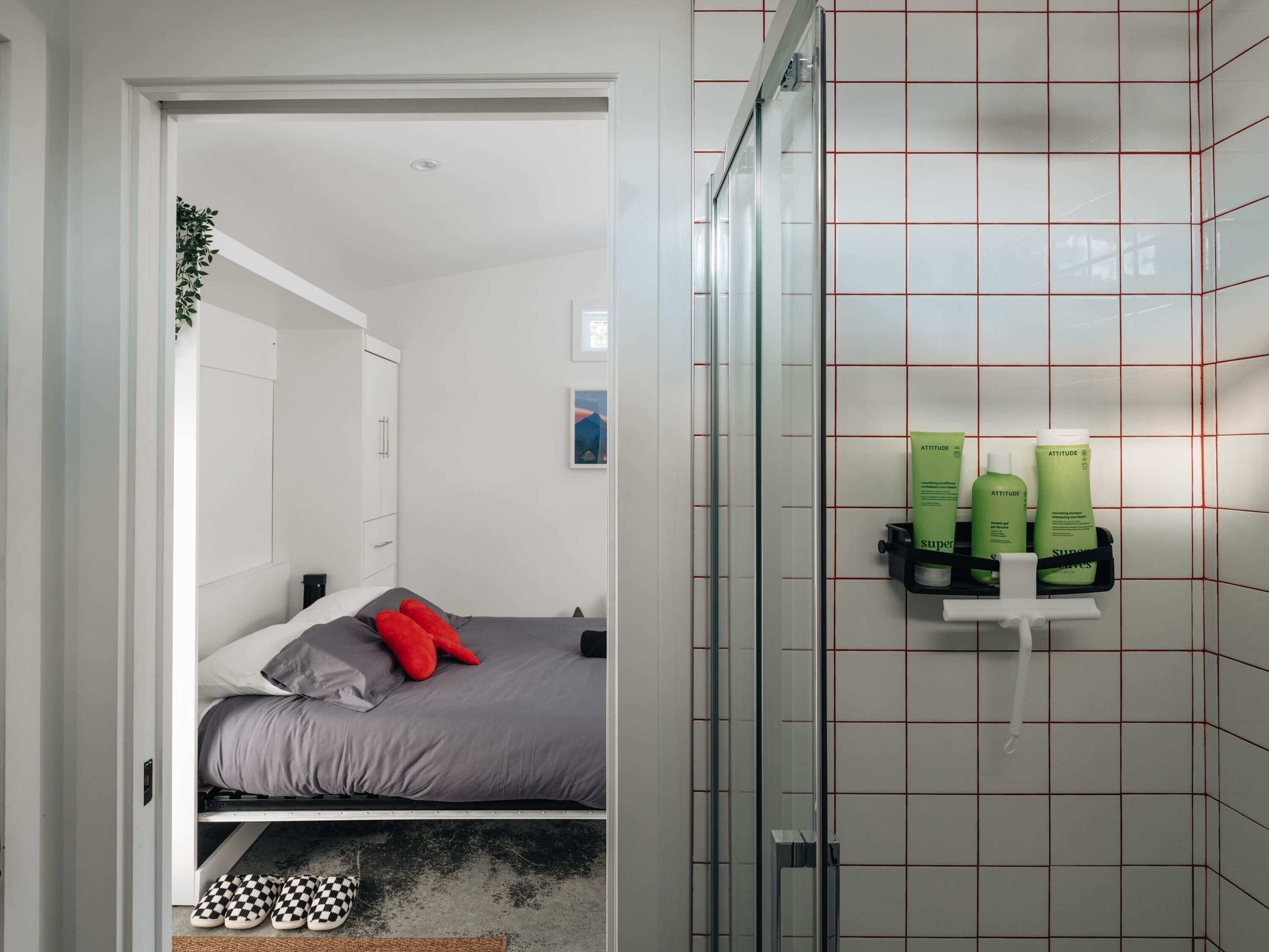 Ein Schlafzimmer mit einem Bett, einem Nachttisch, einem Spiegel und einem Wandregal mit Toilettenartikeln.
