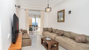 Een moderne woonkamer met een flatscreen televisie, een houten salontafel en een beige bank.
