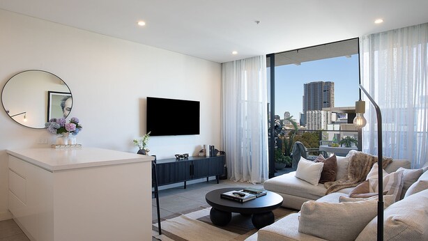 A modern living room with a flat-screen TV, a round mirror, and a sofa. - Riverside Parramatta I90 (Parramatta)