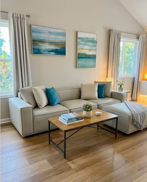 A living room with a sectional sofa, a coffee table, and two paintings on the wall.