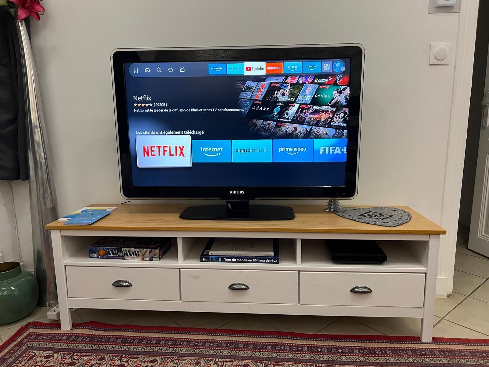 Un televisor sobre un mueble blanco con tapa de madera, mostrando la interfaz de Netflix.