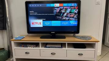 Un televisor sobre un mueble blanco con tapa de madera, mostrando la interfaz de Netflix.
