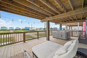 En træterrasse med jacuzzi og loungeområde, med udsigt over en grøn mark.