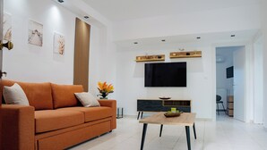 Una sala de estar moderna con un sofá, una mesa de centro y un televisor de pantalla plana montado en la pared.