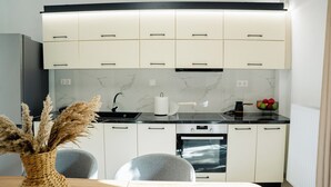 Una cocina moderna con armarios blancos, encimera negra y horno integrado.