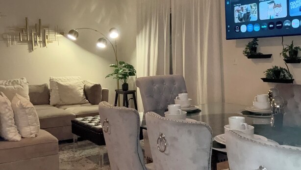 Una sala de estar moderna con comedor, un televisor de pantalla plana en la pared y un ventilador de techo.