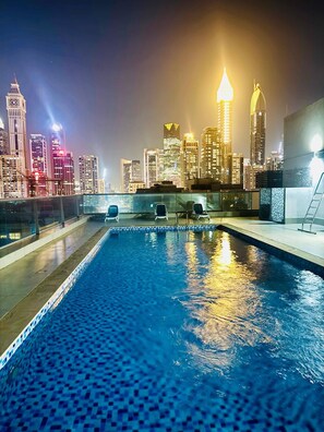 Una piscina sul tetto con vista sulla linea dell'orizzonte cittadina di notte.