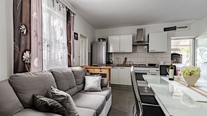 Eine moderne Küche mit Essbereich, einer Couch mit Kissen und einem Fenster mit Vorhängen.
