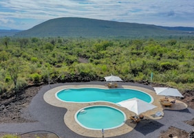 Una piscina al aire libre, sombrillas, sillones reclinables de piscina