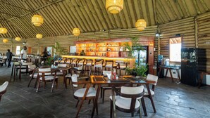 A restaurant with wooden tables and chairs, a bar area, and hanging lights. - Sleeping Warrior Camp Elementaita (Gilgil)