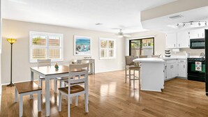 Una cocina amplia con armarios blancos, una isla central y un comedor con sillas y mesa.