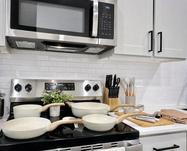 Una cocina con microondas, estufa y ollas.
