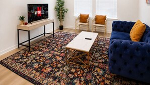 Un salon comprenant un téléviseur, un canapé, une table basse et un tapis à motifs.