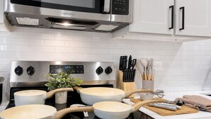 Une cuisine équipée d’un four à micro-ondes, d’une cuisinière et de casseroles en acier inoxydable.